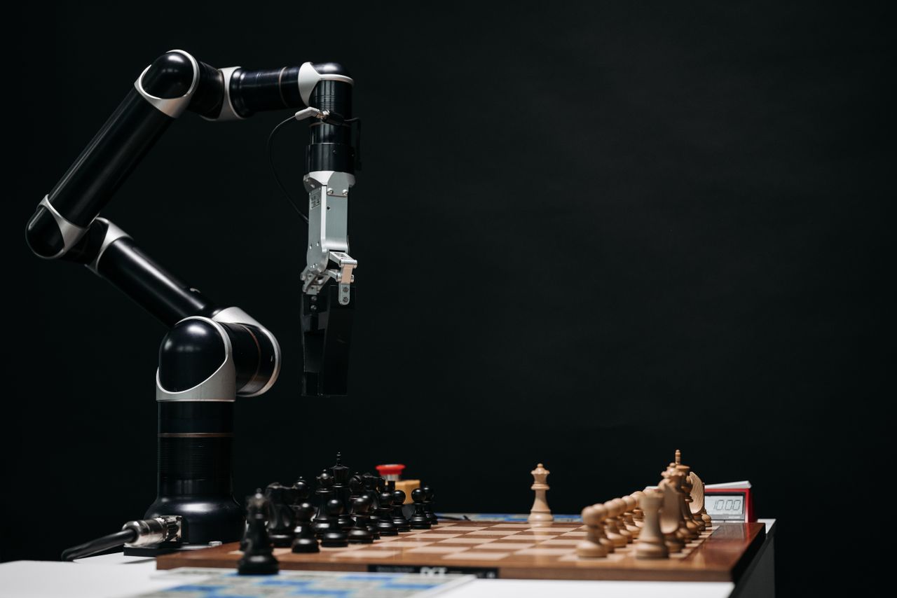 A robotic arm engages in a chess match, showcasing AI and robotics in a studio setup.